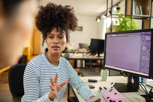Designer discussing project at computer in modern office