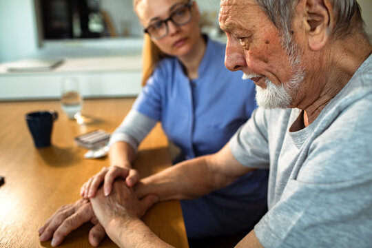 Caregiver comforting senior man at home