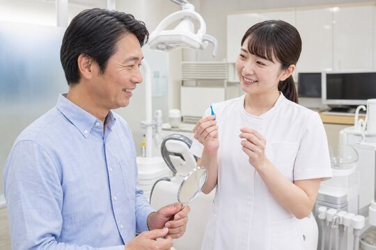 歯科衛生士が男性患者にフロスと歯間ブラシを説明する