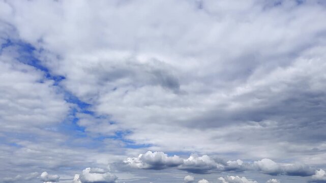 Expansive cloudy sky with layered gray formations and patches of blue, creating a soft atmospheric weather background with shifting light and a calm transitional mood.