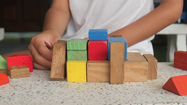kid playing with wooden bricks. Children constructing house from colored elements. Bright toy building - real estate theme.
