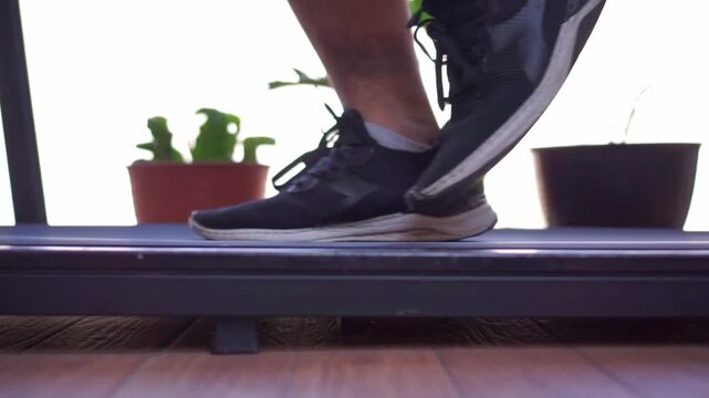 Person's feet running on treadmill, home cardio exercise, fitness workout routine, healthy lifestyle footage scene.