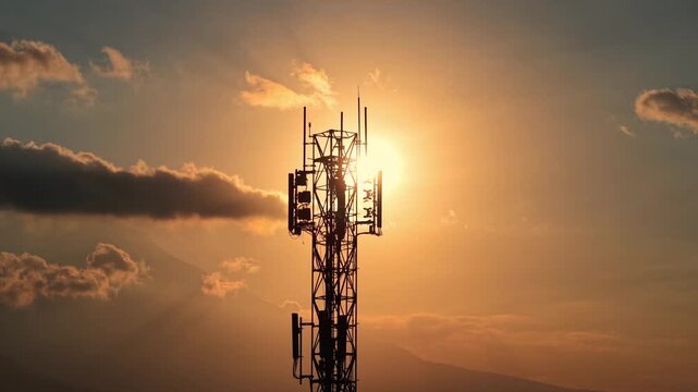 Cellular network tower silhouetted against dramatic sunset with clouds. Telecommunication, signal, and wireless technology concept footage.