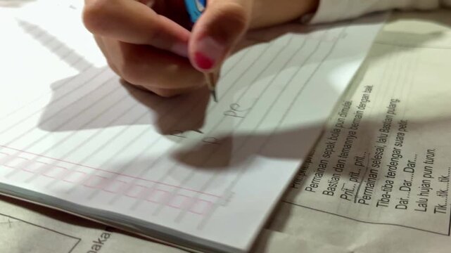 hand practicing handwriting with pencil, lined paper visible, children's learning and education concept.