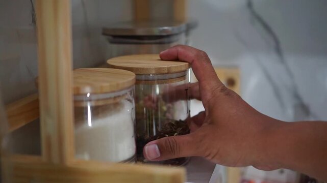 hand take out tea storage jar on wooden shelf, kitchen organization and food storage concept.
