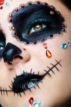 Halloween beauty close-up photography of female face. Beautiful woman adorned with Santa Muerte makeup.
