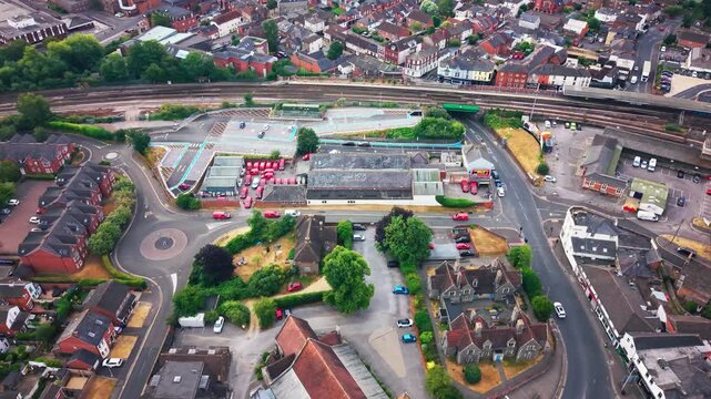 Aerial drone footage overlooking a postal delivery yard with mail vans railway line small roundabout and terraced houses in an English town