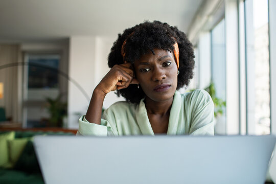 Concerned woman looking at laptop at home office