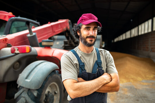 Confident farmer with tractor in grain barn