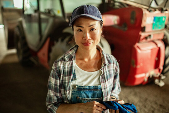 Female farmer portrait in barn with tractor