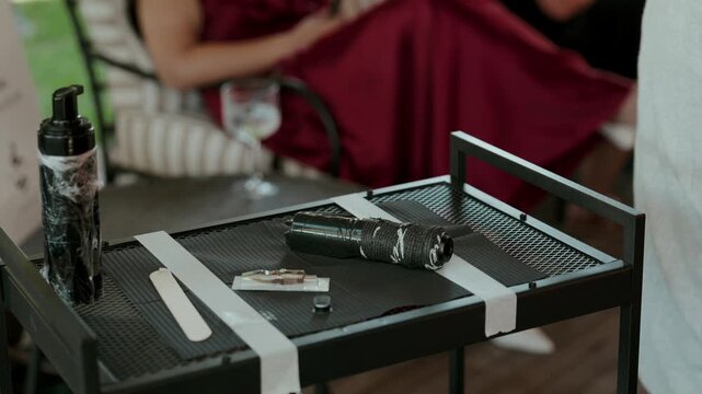 Wrapped tattoo machine bottle and supplies laid out on a black mesh work table