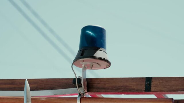 Blue rotating beacon light mounted on the wooden ladder rail of a vintage fire truck