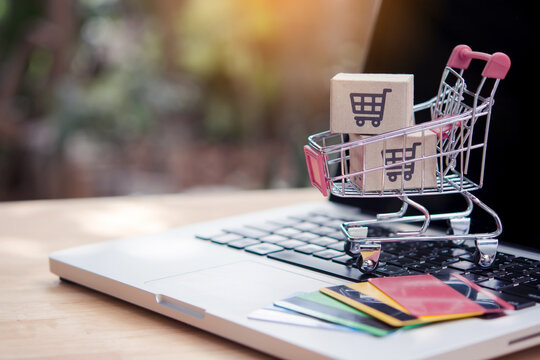 Shopping online. Credit card and cardboard box with a shopping cart logo in a trolley on laptop keyboard. Shopping service on The online web. offers home delivery