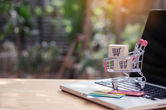 Shopping online. Credit card and cardboard box with a shopping cart logo in a trolley on laptop keyboard. Shopping service on The online web. offers home delivery