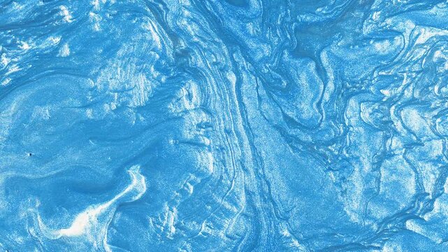 Abstract macro shot of smooth light blue metallic fluid liquid swirling with silver glitter sparkle particles. Luxurious pearlescent paint motion background for creative design.