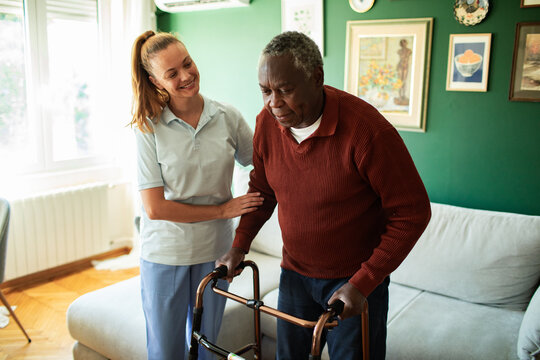 Caregiver assisting senior man with walker at home