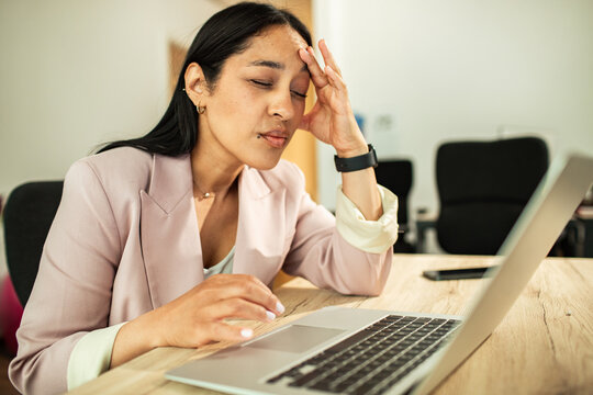 Stressed businesswoman working on laptop in office