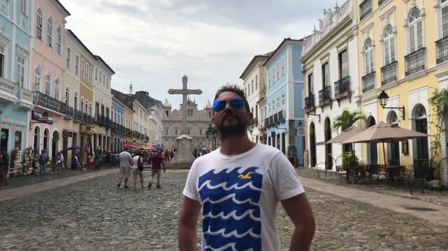 Confident bearded man with sunglasses enjoying his vacation while visiting the colorful colonial architecture of Pelourinho. A famous historical landmark and touristic destination in Salvador. Bahia