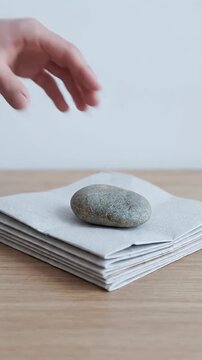 Hand Holding Smooth Stone Above Paper Stack for ESG Balance, Sustainability, Nature, Environment, and Mindful Daily Responsibility Minimalist Studio