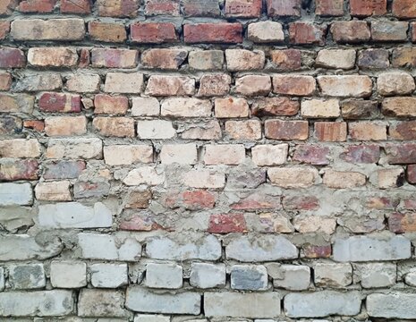 An old weathered brick wall background featuring a combination of vintage red clay bricks and gray silicate bricks with rough concrete mortar joints in a rustic industrial style.