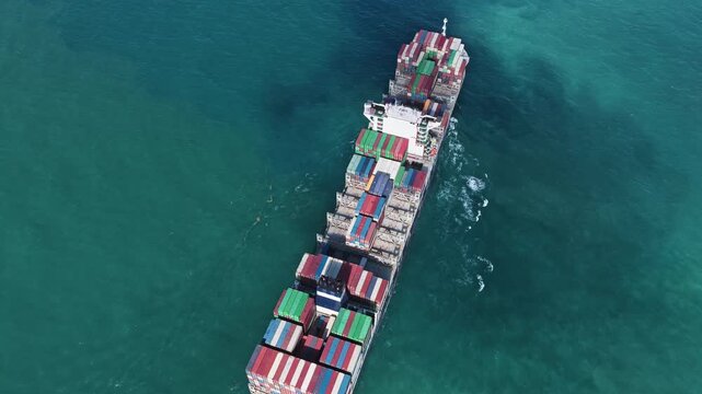Shipping logistics. Commercial shipping. Cargo ship at sea, aerial top view. Freight container loaded on cargo tanker. Aerial cargo ship passing harbor. Cargo business. Container ship