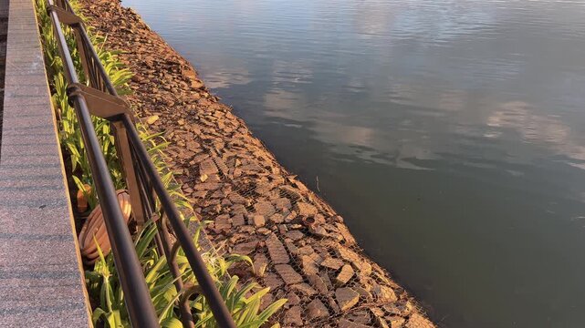 Riverside Promenade Overlooking Stone Riprap Bank at Sunset