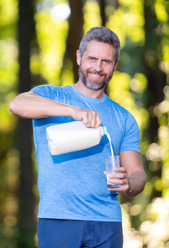 Man pours Milk into glass. Healthy sport nutrition outdoors. Dairy drink. Glass of milk for Healthy man. Milk for healthy living. Dairy protein source. Active man outdoors. Milk nutrition concept.
