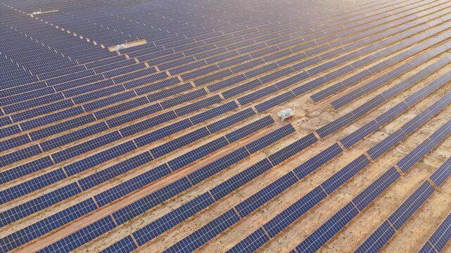 Solar photovoltaic panels at sunrise/sunset; wind turbine power plant; new energy