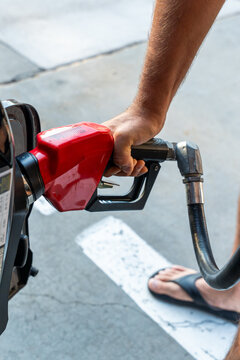 Vertical image of a person refueling a vehicle with a pump nozzle, symbolizing rising fuel prices, fuel shortages, energy costs, and consumer concerns during a fuel crisis. Economic pressure and trans