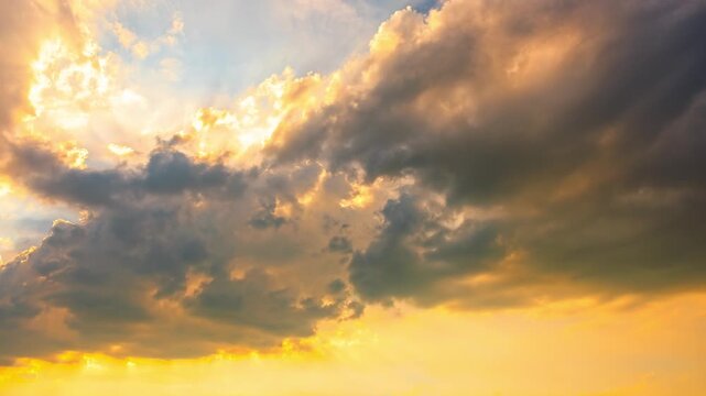 Dramatic golden sunbeams breaking through dark storm clouds at sunset