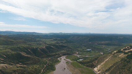 Aerial shot of grand Xilamulun Grand Bridge spanning Xilamulun River. Magnificent transportation infrastructure set against Inner Mongolia grassland mountain‑valley natural landscape. © Guiyi