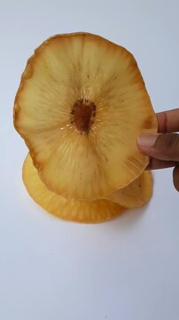 Hand holds dried breadfruit chip snack. Traditional Indonesian Breadfruit Chips Made from Fried Sliced breadfruit or Sukun Fruit Isolated on White Background.