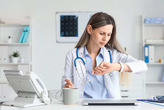 Healthcare professional time management and busy schedule, female doctor checking watch in modern clinic office