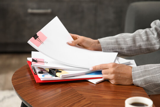 Businesswomans hands with documents on table in office, closeup