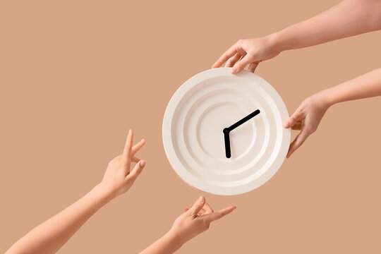 Female hands holding wall clock on beige background