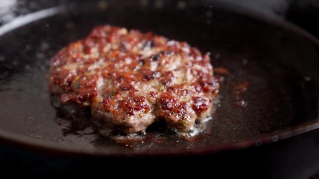 Homemade Burger Patty Sizzling in a Cast Iron Skillet