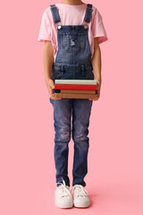 Fototapeta premium Little girl with stack of books on pink background