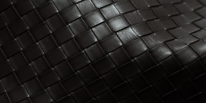 close-up of a jet-black woven leather texture featuring a geometric pattern of rectangular strips arranged and layered in an orderly fashion
