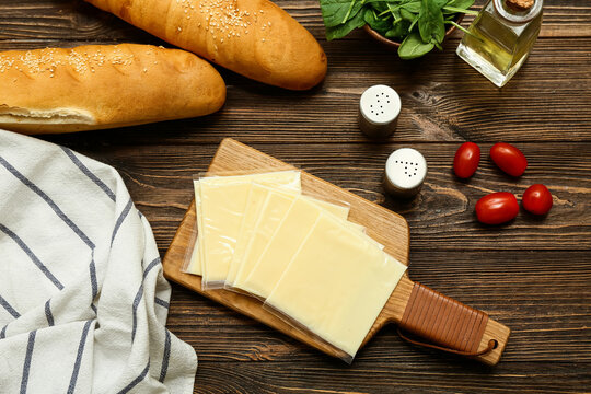 Board with slices of delicious processed cheese, fresh tomatoes and bread on wooden table