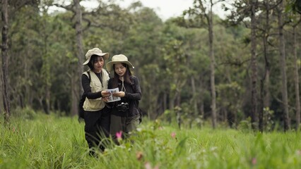 Fototapeta premium Asian Female Travelers Walking With Paper Map In Wildflower Meadow