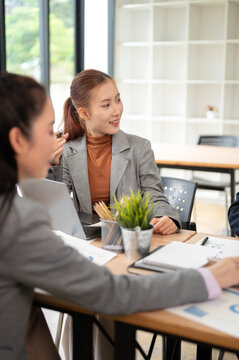 Business meeting with women collaborating around laptop and discussing project plans