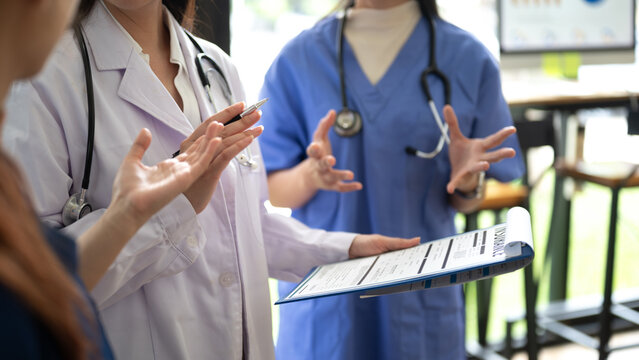 Doctors and nurses discussing patient care and medical documents in healthcare workplace