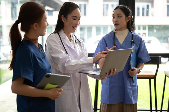 Healthcare professionals collaborating on medical records and patient care using laptop