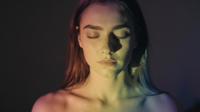 Serene Young Woman with Eyes Closed in Colorful Light