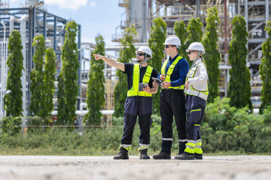 Oil refinery engineers team with tablet pointing at industrial plant facility, Petroleum plant workers discussing project outdoors, Energy industry professionals inspecting industrial site