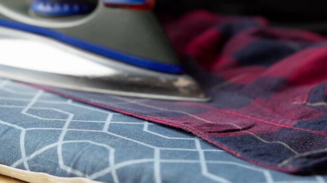 Ironing a plaid shirt to remove wrinkle, with steam rising