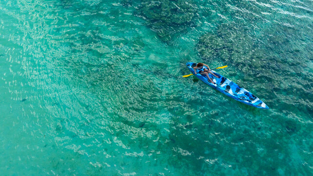 Aerial view of a woman and a young man kayaking on clear blue waters at Andaman Island. She does water sports activities	
