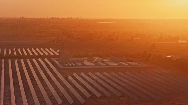 Solar photovoltaic panels at sunrise/sunset; wind turbine power plant; new energy