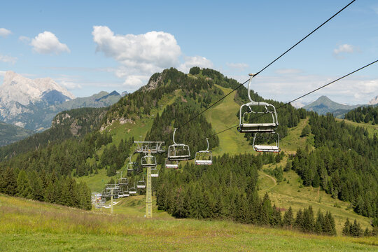 Col dei Baldi, Italy. Chairlift crossing alpine meadows with dramatic Dolomite mountain scenery