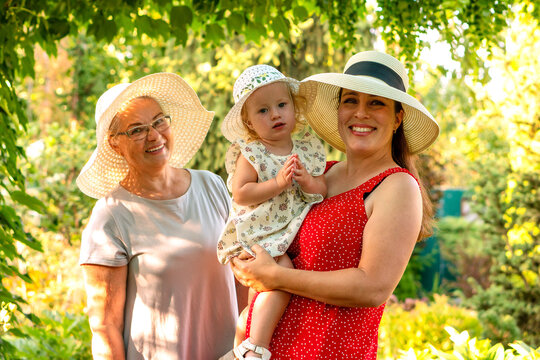 Three Generations Smiling Together In White Summer Hats